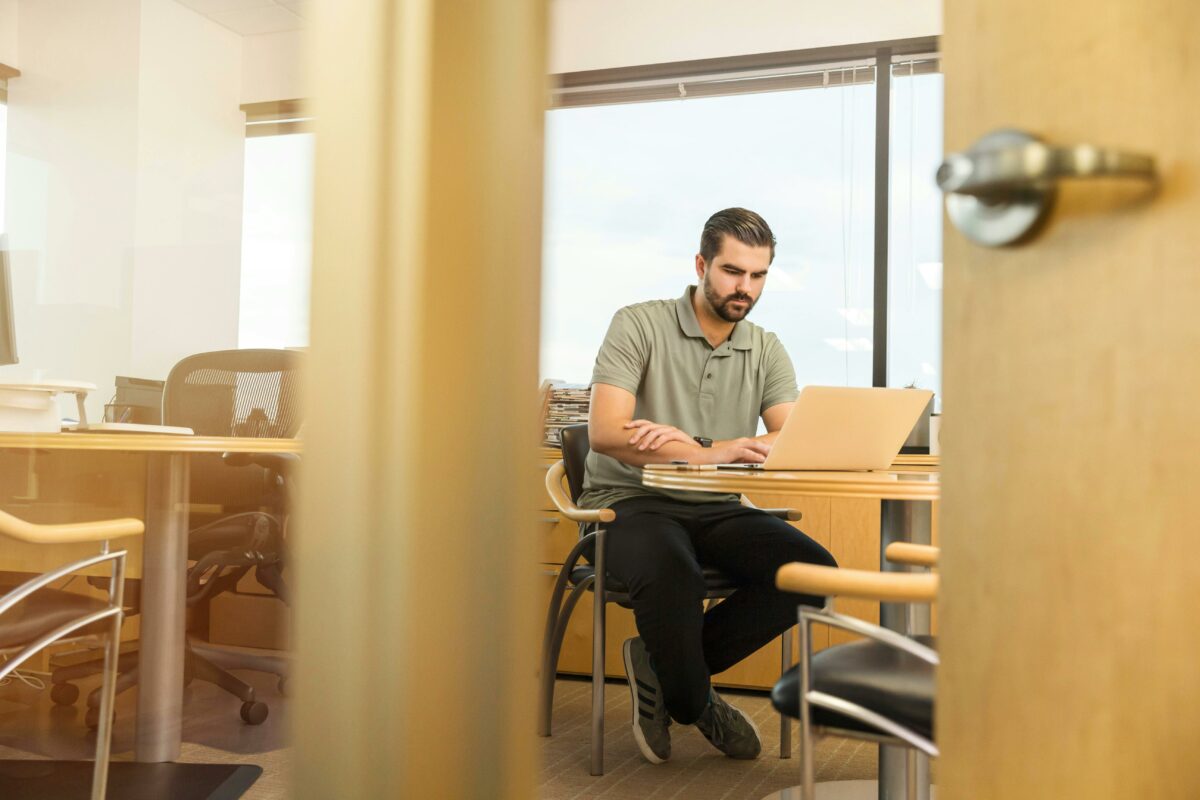Een man werkt op zijn laptop in een kantoor